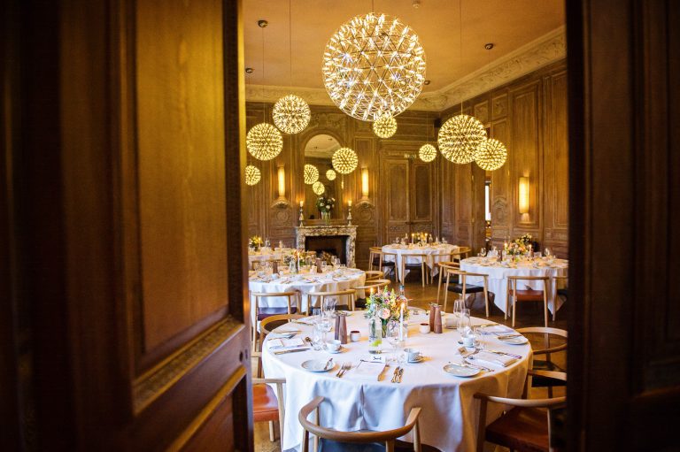 A door opens onto the dining room at Cowley Manor. Tables are all set for a wedding.