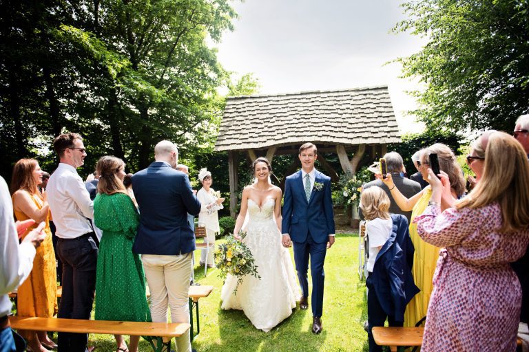 Bride and groom walk down the wedding isle at the end of their outdoor wedding ceremony Cripps Barn