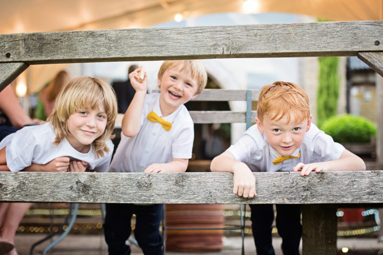 Storytelling image of children peering through two wooden slats looking up to mischief!