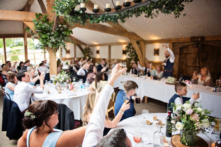 Candid photo of guests celebrating the end of speeches by raising their glasses in the air.