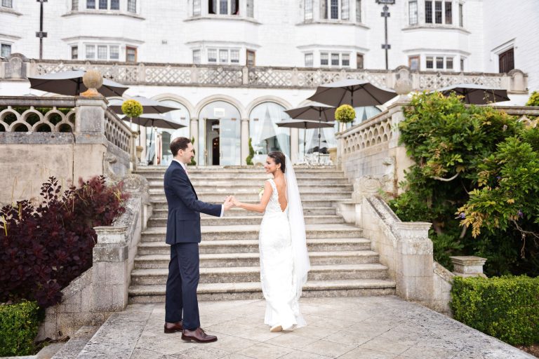 Groom admires his bride at the back of the impressive Danesfield House.