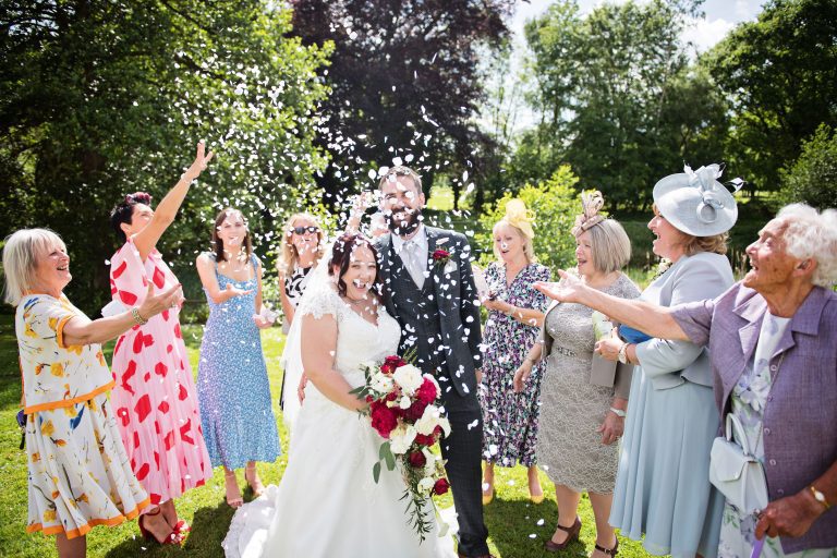 Bride and groom have confetti thrown over them by close wedding guests.