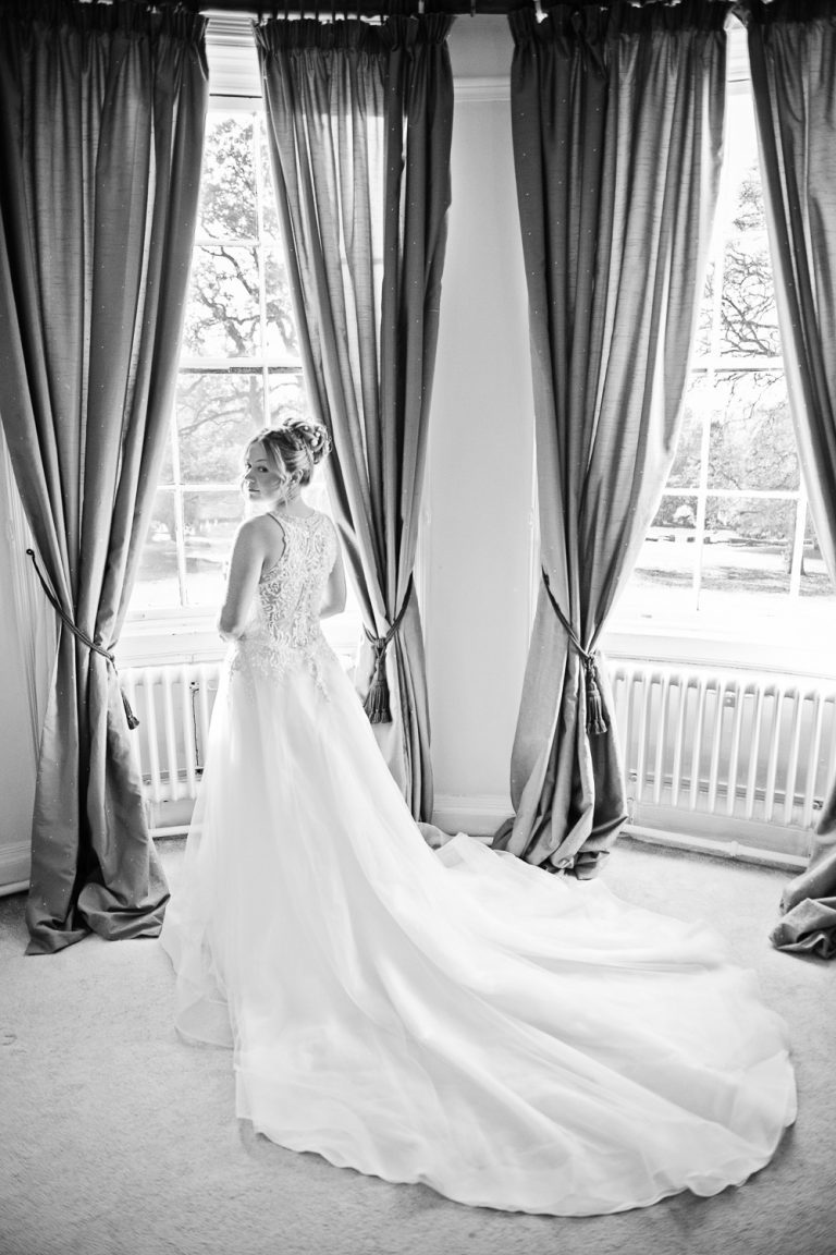B&W portrait image of bride in front of a bay window in the bridal suite at Eastington Park.