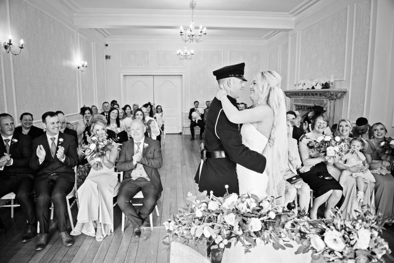 B&W image of a bride and her groom (dressed in military uniform as they are announced husband and wife at their wedding at Eastington Park