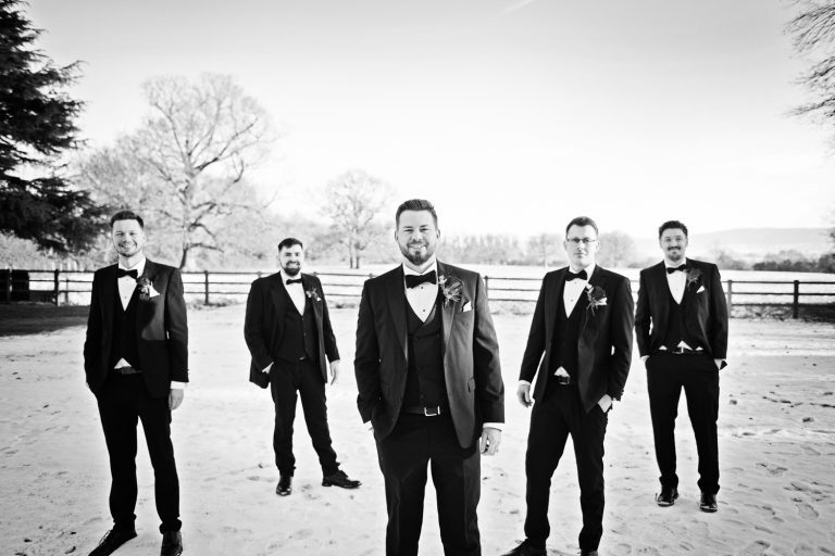 B&W photo of groomsmen standing smartly in the snow at Eastington Park