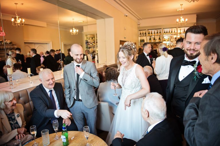 Informal photo of wedding guests chatting to the bride and groom.