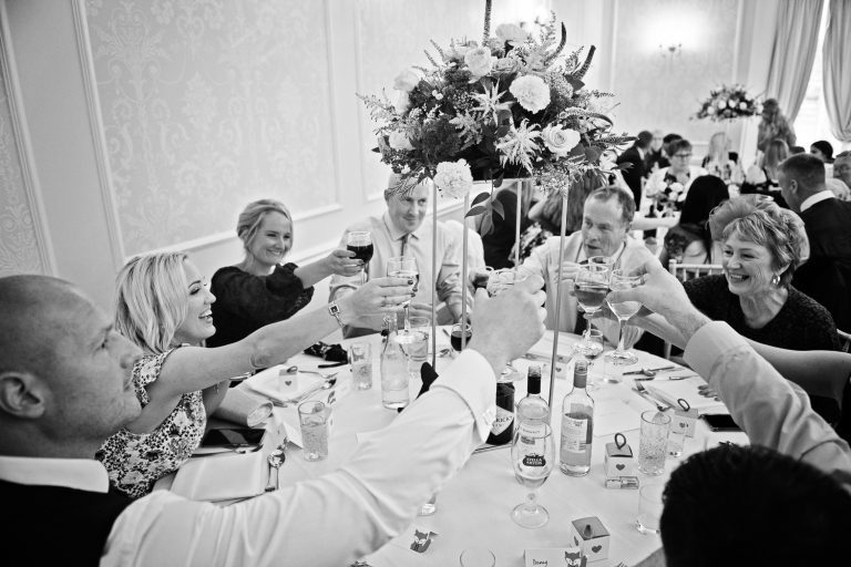 B&W image of wedding guests raising their glasses