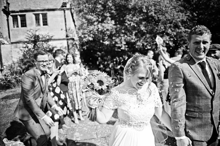 Candid photo of Bride and groom getting showered with confetti. B&W photo.