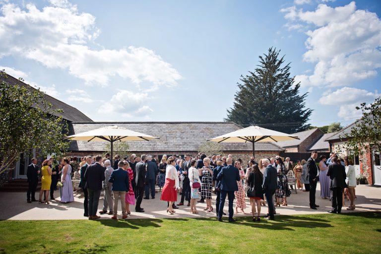 Overview of wedding guests chatting in the grounds outside at Farbridge.