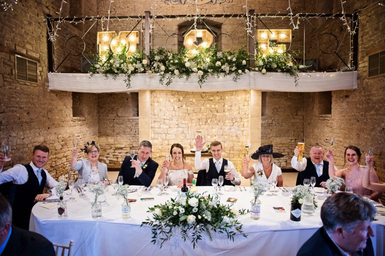 Fun image of top table at Great Tythe Barn raising their glass in celebration.