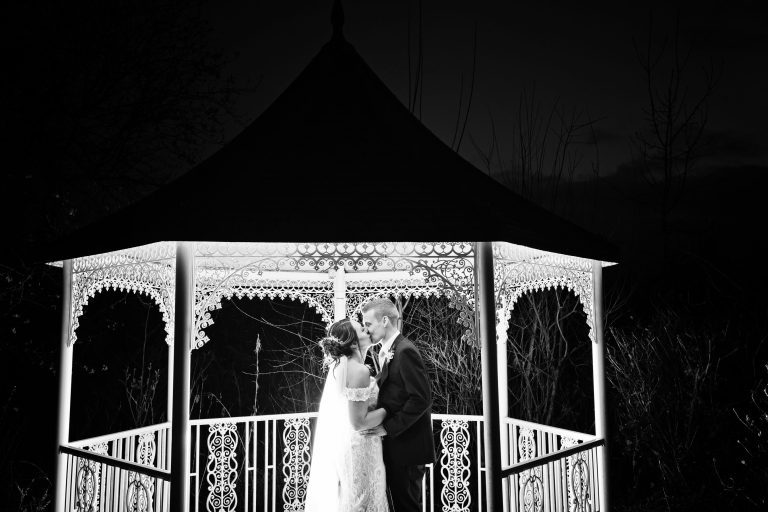 B&W image of bride and groom kissing in the dark (they are lit up).