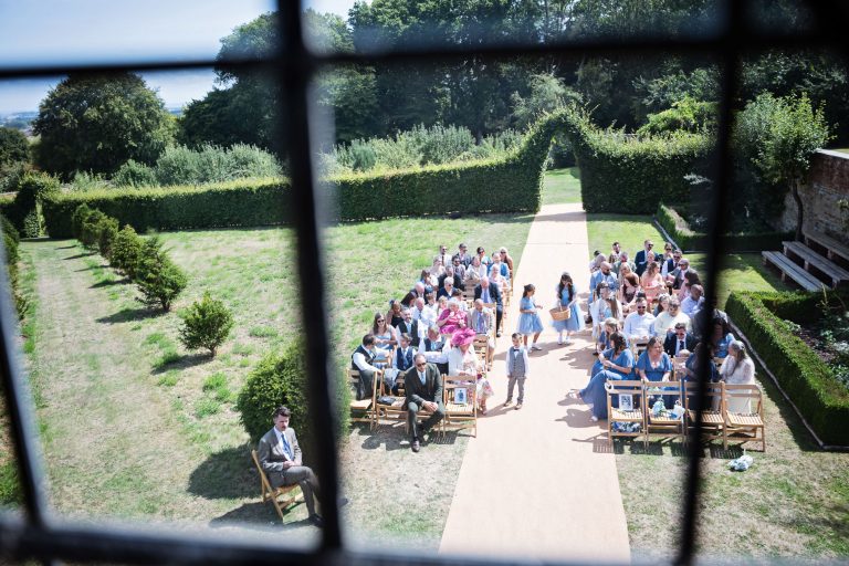 Photograph through the window looking down on wedding ceremony taking place. You can see the flower girls distributing the confetti.
