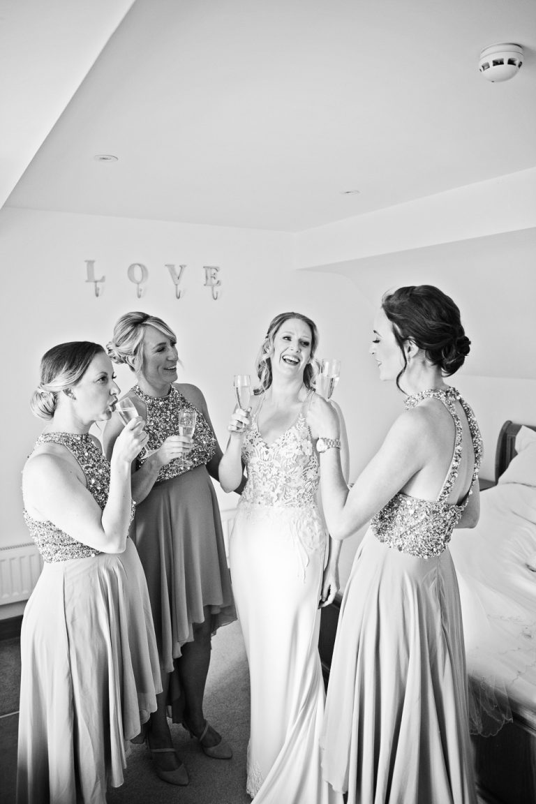 B&W portrait photo of bride and bridesmaids celebrating.