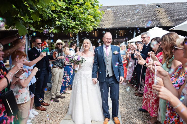 Wonderful image of bride and groom walking in between their guests who are blowing bubbles instead of confetti.