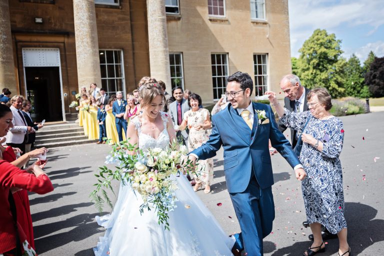 Bride and groom get showered with confetti by their wedding guests.