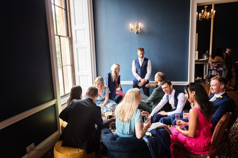 Candid photo of guests indoors chatting at a wedding.