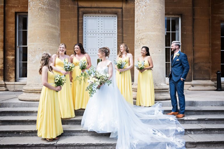 Team bride on the steps at Leigh Court. Bridesmaids wearing yellow dresses.