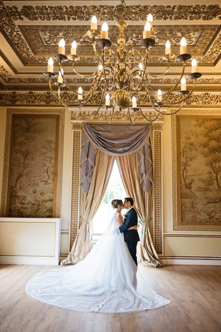 Portrait photo of bride and groom kissing in an elegant state like room at Leigh Court.