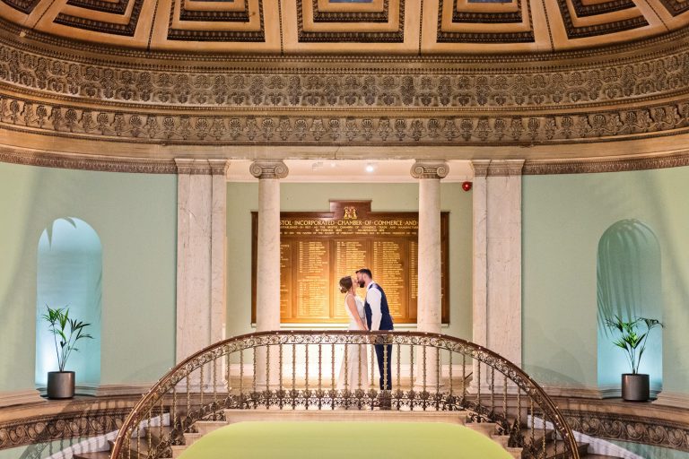 Bride and groom kiss at the top of the grand stairs at Leigh Court.