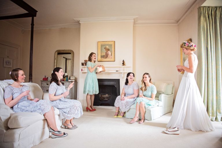 Bridesmaids gasp as they see the bride in her wedding dress for the first time.