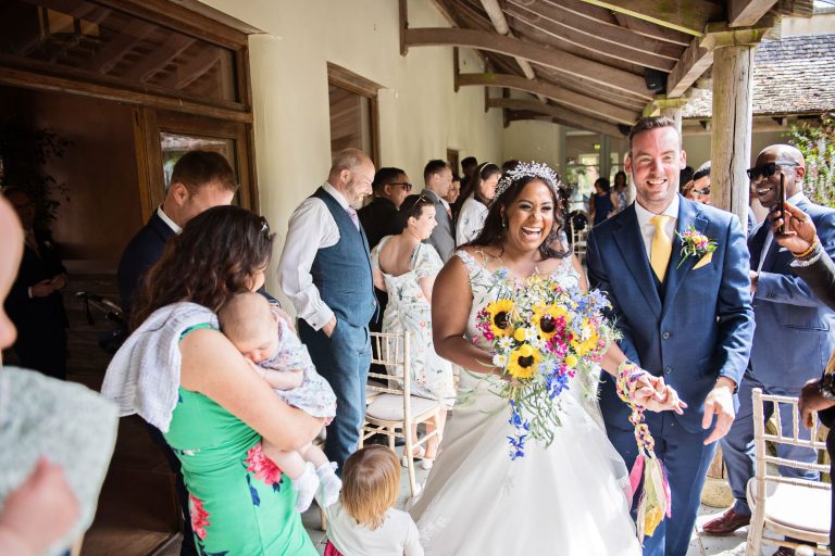 Bride and groom smiling and walking through their wedding guests after getting married in the Cloistered Courtyard at the Matara