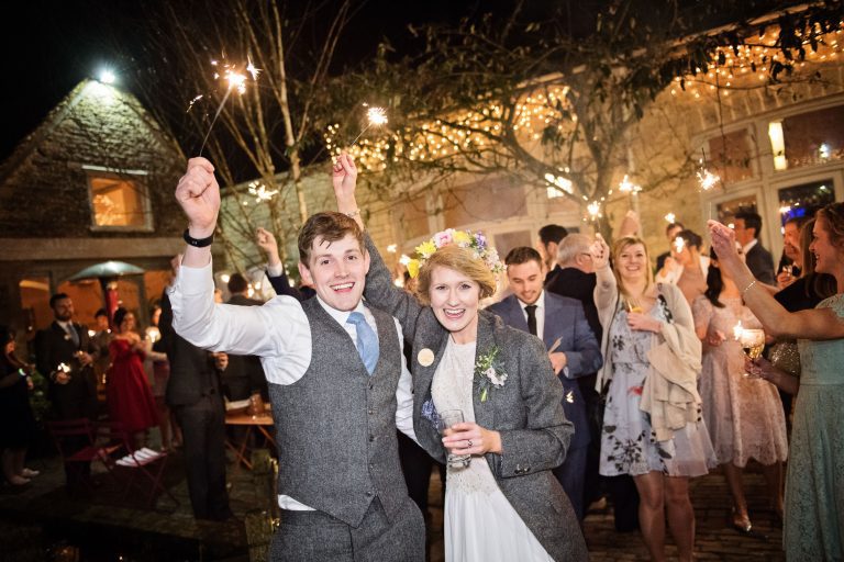 Bride and groom and their wedding guests enjoying night time sparkers.
