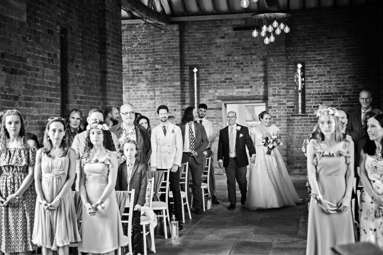 B&W image of bride and groom walking down the wedding isle at Mickleton Hills Farm.