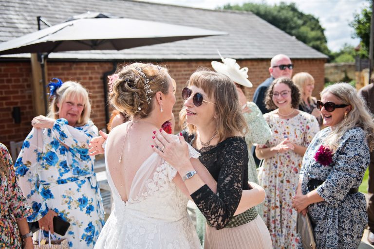 Bride getting hugged and congratulated by her friends at her wedding.