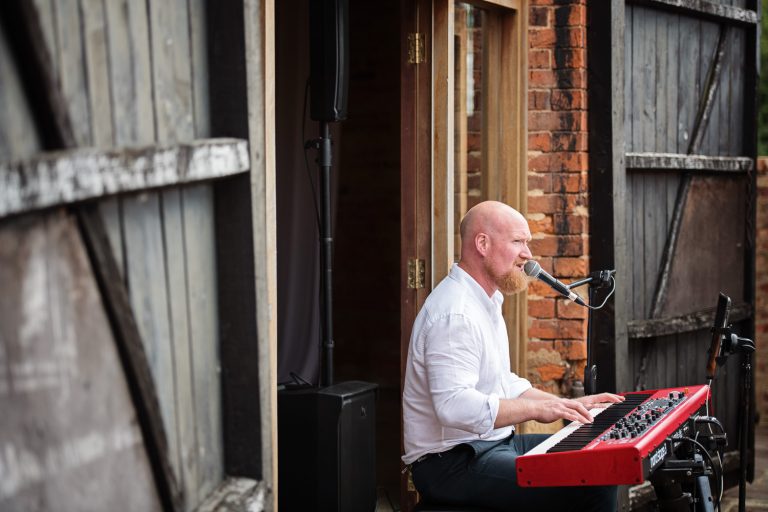 James Roscoe Pianist/Musician doing his thing and entertaining wedding guests with his keyboard and singing in the doors of the barn at Mickleton Hills Farm.