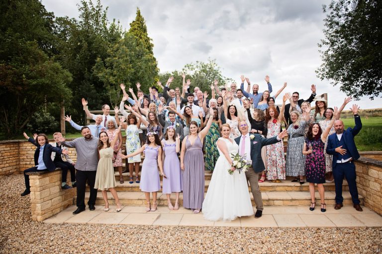 Wedding party (everyone) on the steps with their hands in the air (like they don't care) at Mickleton Hills Farm.
