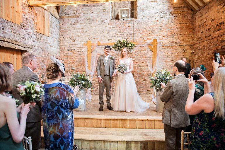 Bride and groom finish their wedding ceremony with the guests clapping.