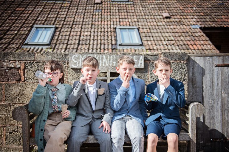 Four boys sat on a smoking bench eating crisps and pretending to smoke.