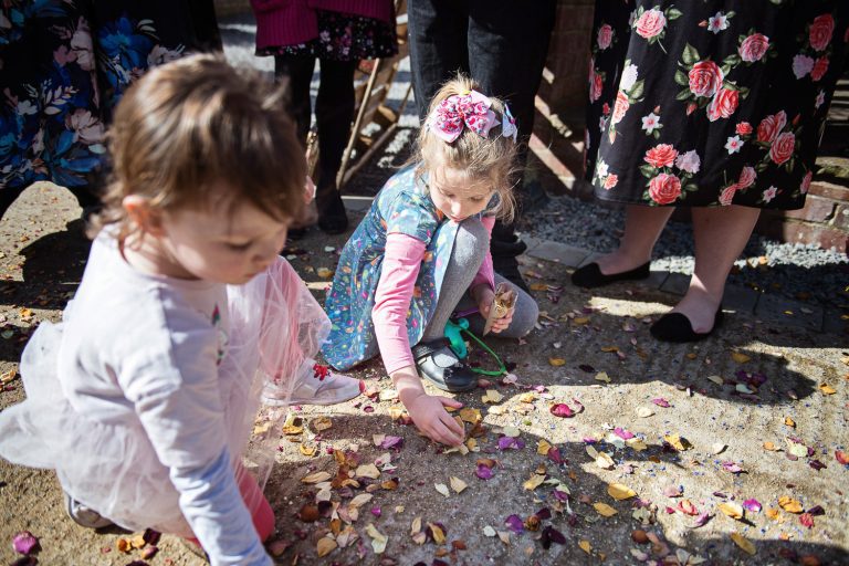 Confetti on the floor being collected by young flower girls.