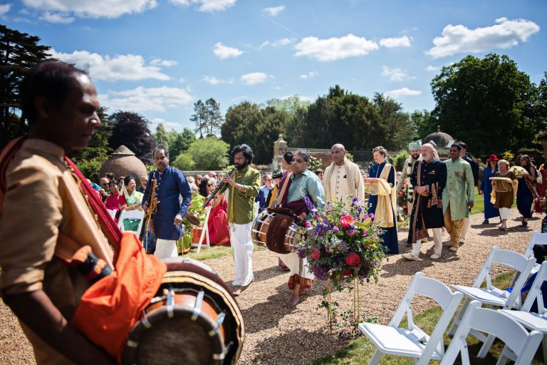 Procession of groom and family arriving being accompanied by musicians at the start of the Hindu ceremony.