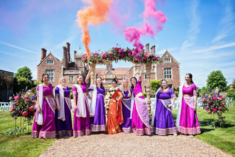 Hindu Bridal party holding smoke bombs in the air. Sari's and smoke very colourful.