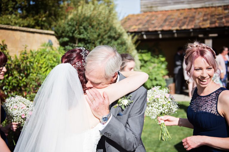 Candid storytelling image of brides father hugging the bride.