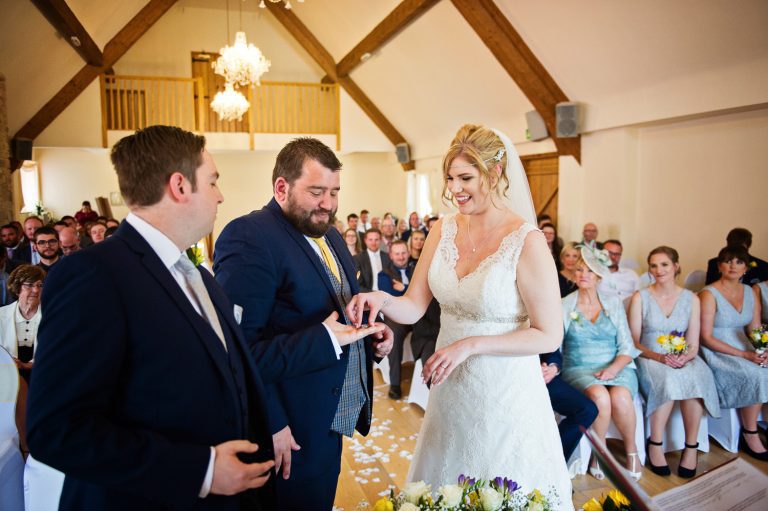 Candid photo of Bride and groom exchange wedding rings