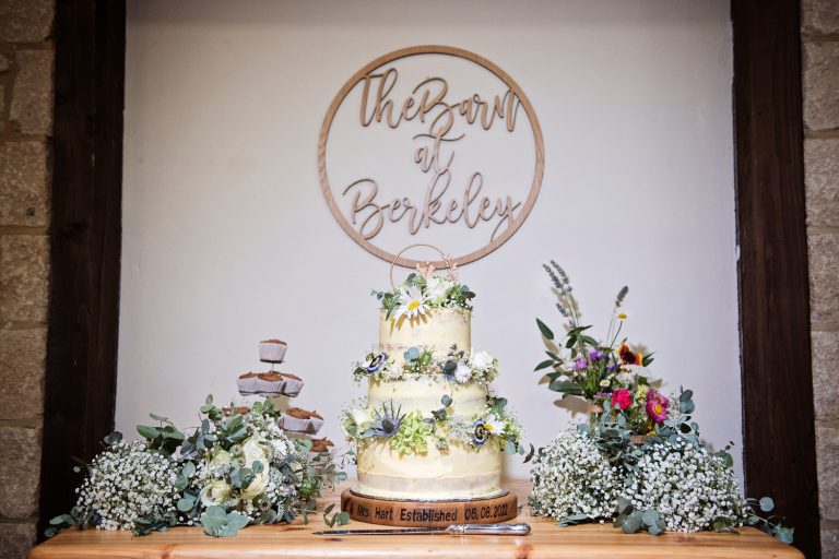 Beautiful tiered wedding cake with The Barn at Berkeley sign behind it.