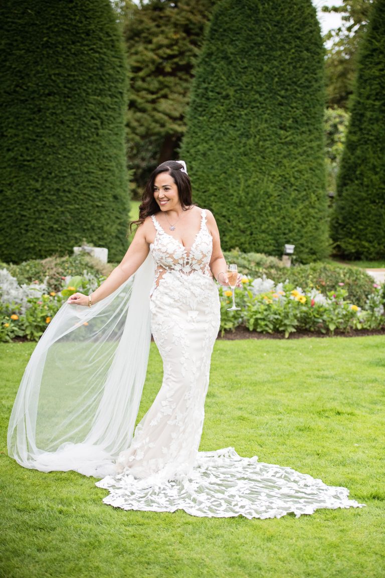 A bride plays with her wedding veil in the gardens at Lygon Arms.