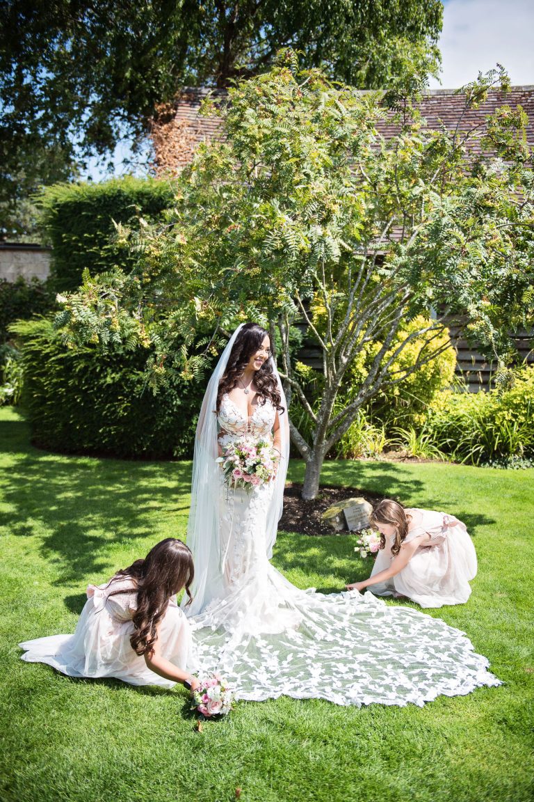 A bride has her wedding dress laid out by her flower girls in the gorgeous Cotswold gardens.
