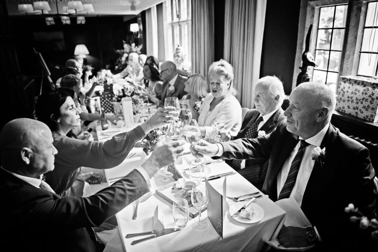 B&W photo of wedding guests cheering each other.