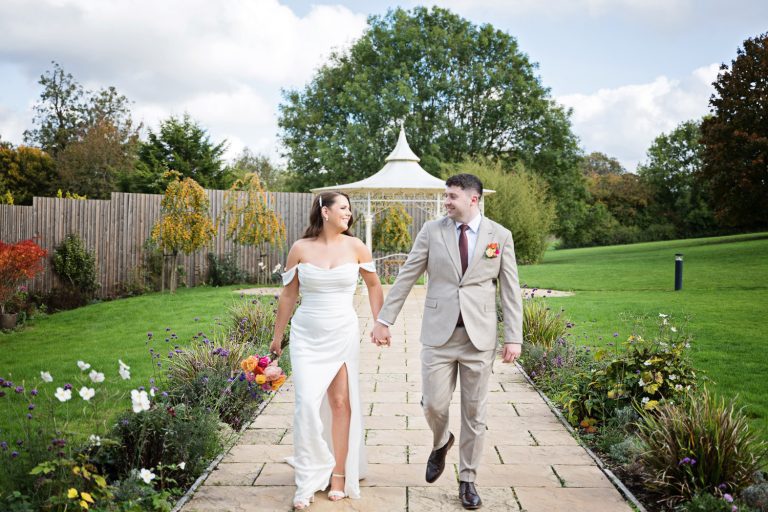 Bride and groom holding hands as they walk towards the camera. Relaxed candid photo.