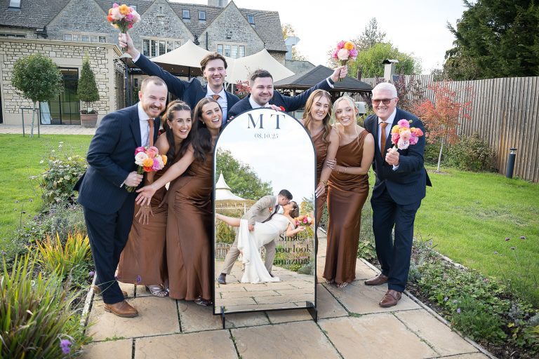 Bridal party with a large mirror with the bride and groom being reflected doing the dip.