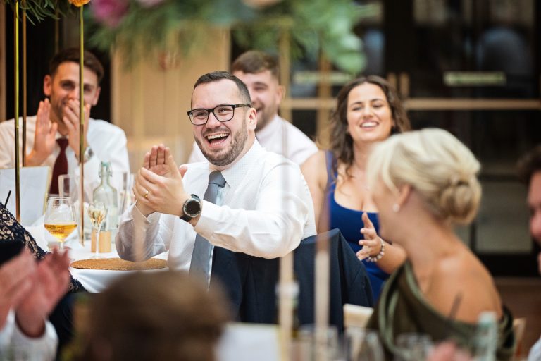 Wedding guest claps in appreciation of the end of wedding speeches.