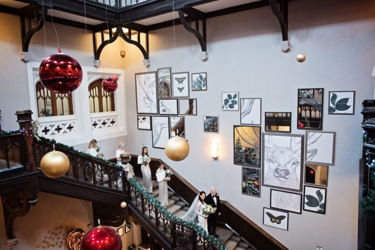 Bride and her father walk down the magnificent stairs at Tortworth Court. Bridesmaids following them.