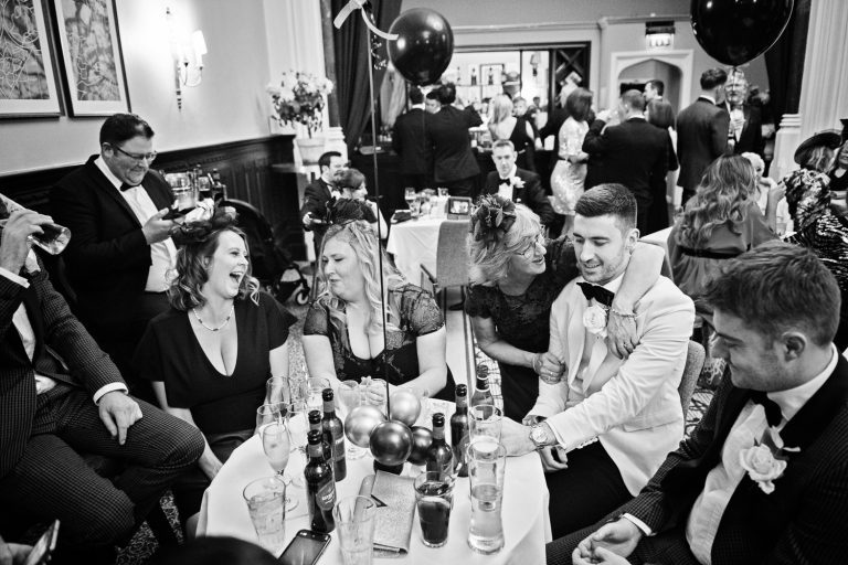 Candid documentary photo of groom enjoying his wedding guests company. B&W photo.