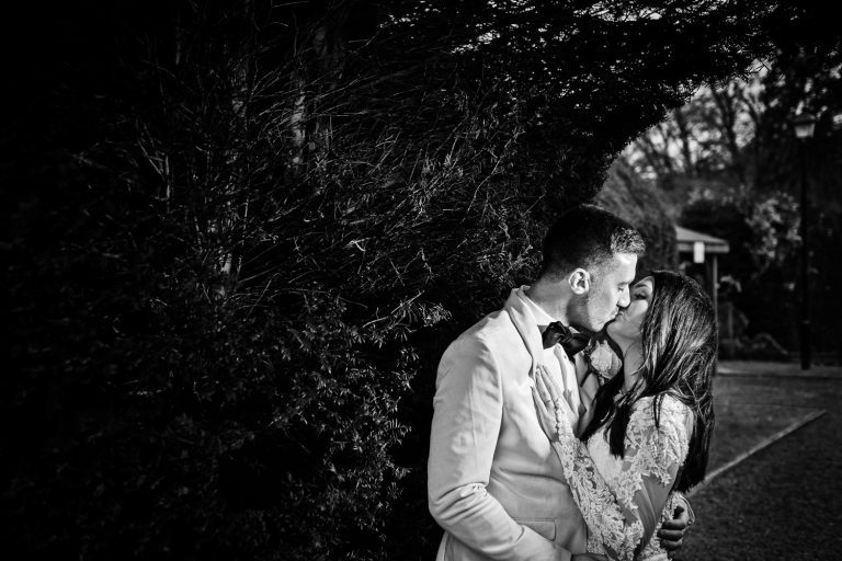 Bride and groom kissing in the winters sunlight. B&W image.