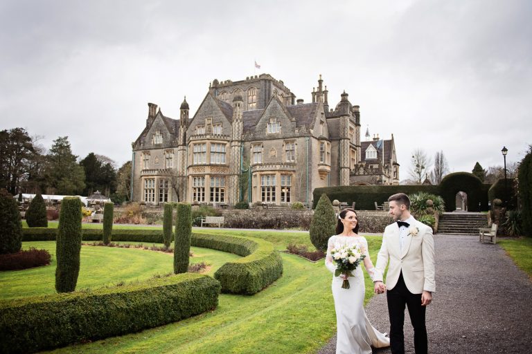 Candid photo of the Bride and groom holding hands and walking, with Tortworth Court in the background.