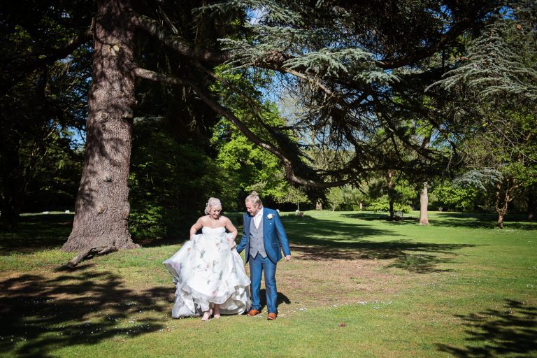 Bride and groom walk along the parkland.