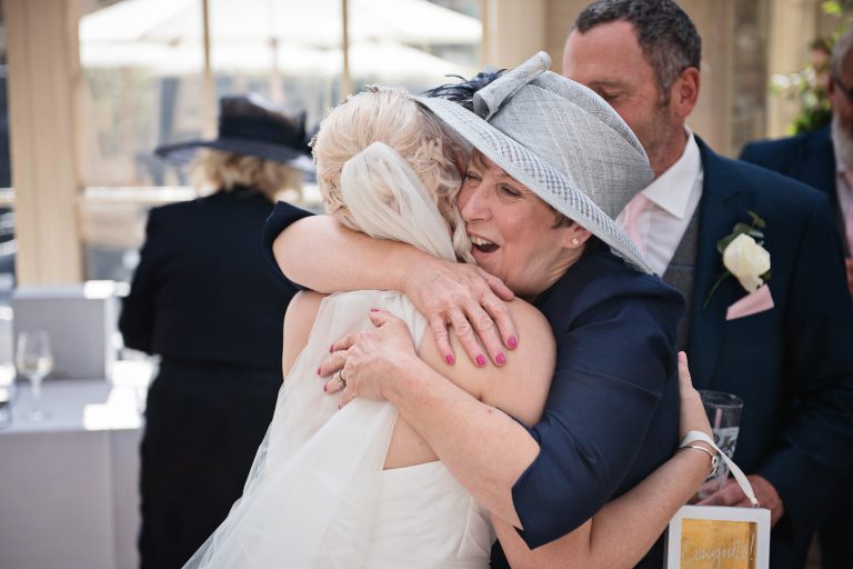 Candid photo of the bride being hugged by the mother of the groom.
